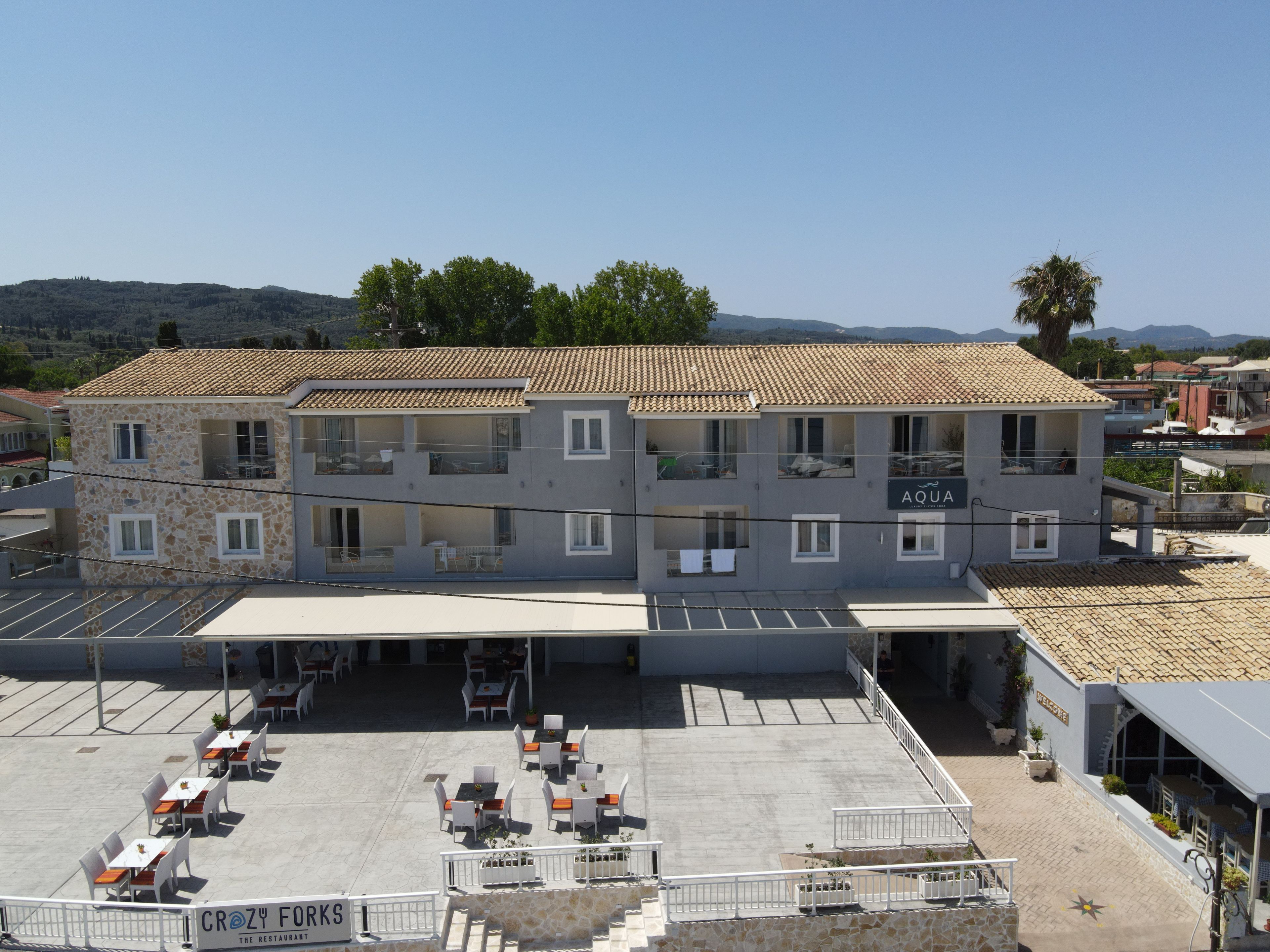 Un bâtiment à deux étages, doté d’un toit en tuiles, d’un espace extérieur couvert avec des sièges et d’une enseigne indiquant « AQUA SPA ».