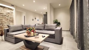 A modern living room with a sectional sofa, a coffee table, and a decorative vase. - Aqua Luxury Suites (Corfu)