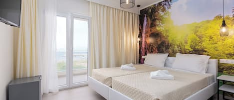 Ett hotellrum med en stor säng, en tv som är monterad på väggen och en vacker väggmålning.