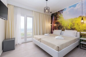 A hotel room with a large bed, a TV mounted on the wall, and a scenic mural on the wall. - Aqua Luxury Suites (Corfu)