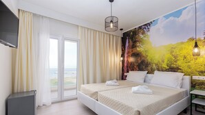 A hotel room with a large bed, a TV mounted on the wall, and a scenic mural on the wall. - Aqua Luxury Suites (Corfu)
