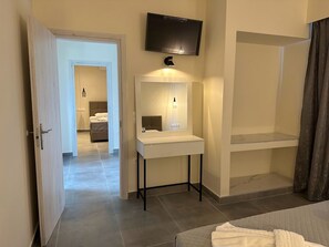 A modern hotel room with a bed, a bedside table, a mirror, and a TV mounted on the wall. - Aqua Luxury Suites (Corfu)