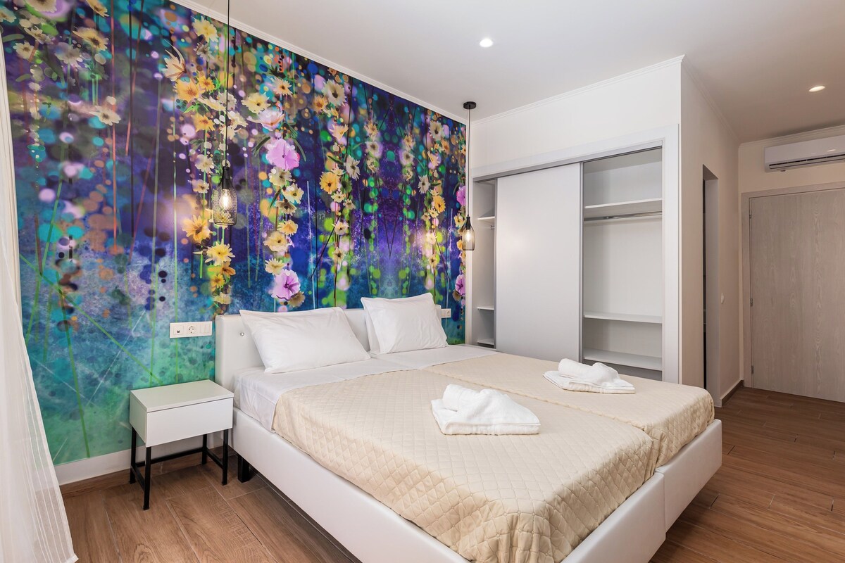 Un dormitorio con una cama grande, una mesita de noche, un armario y una pared con un mural floral.
