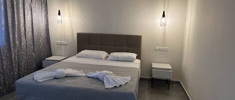 A modern hotel room with a large bed, two bedside tables, and a wall-mounted air conditioner.