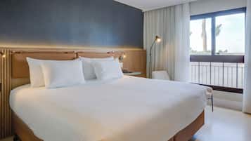 Uma cama grande com lençóis brancos, cabeceira de madeira e mesa de cabeceira com abajur.