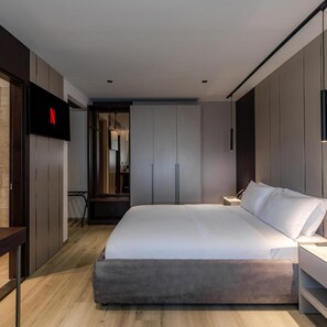 A modern bedroom with a large bed, a TV mounted on the wall, and a wardrobe. - Emery Hotel Pristina (Pristina)
