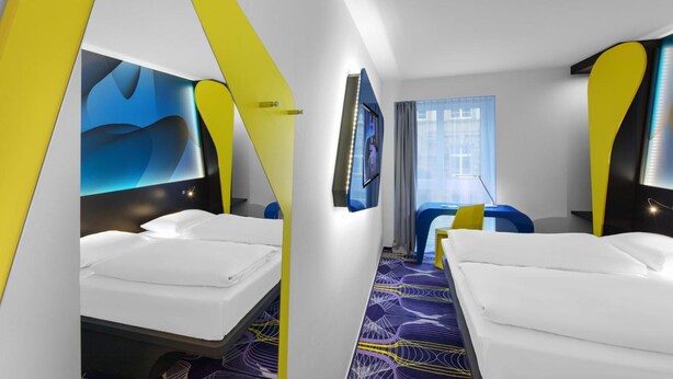 A modern hotel room with two beds, a TV, and a window with curtains. - Prize by Radisson, Erfurt City (Erfurt)