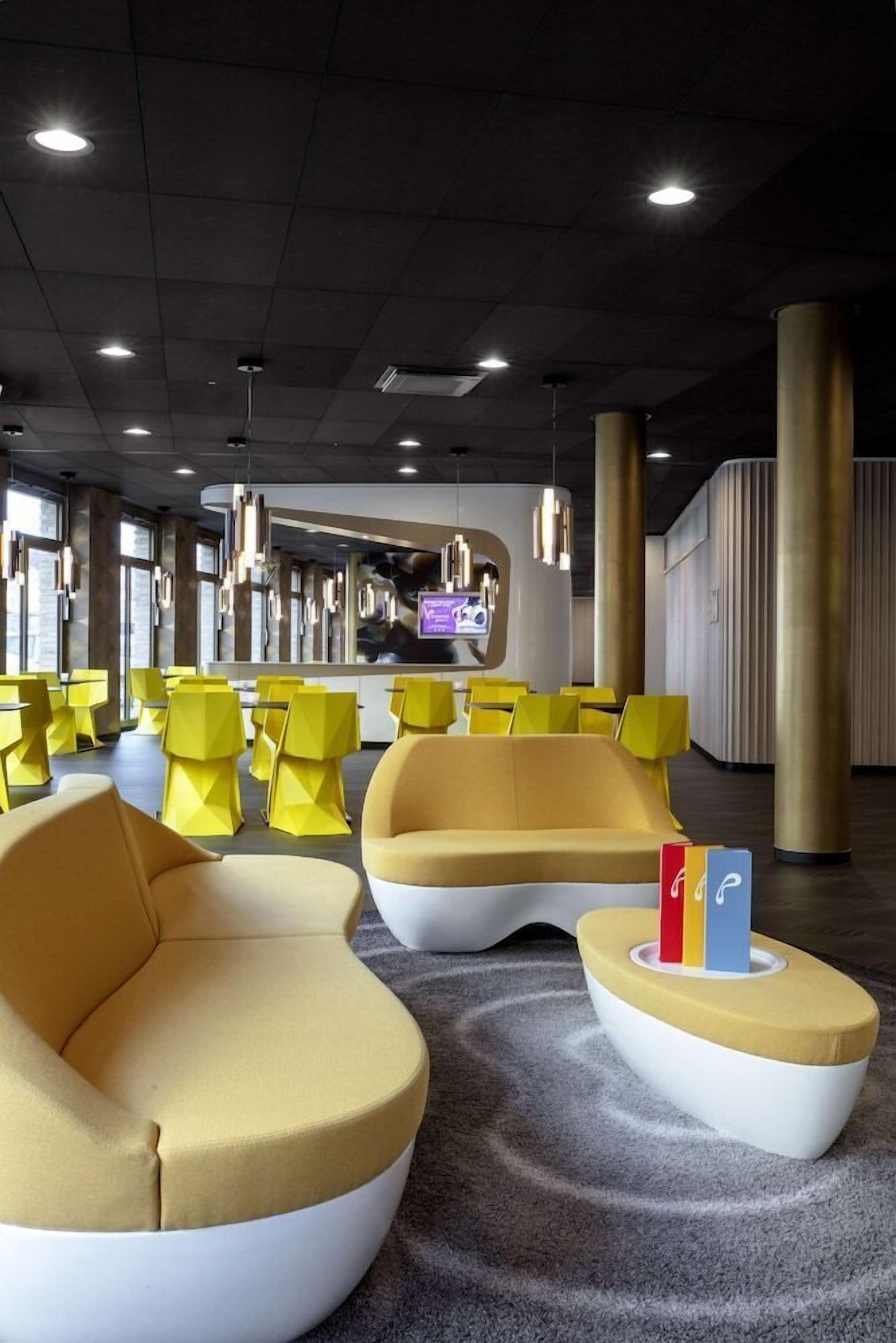 A modern interior with yellow and white seating, a reception area, and large windows.