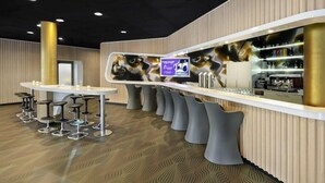 A modern bar area with a long counter, multiple stools, and a television screen. - Prize by Radisson, Erfurt City (Erfurt)