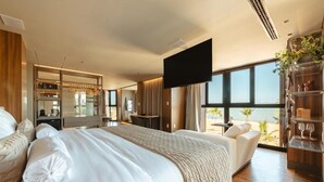 A modern hotel room with a large bed, a seating area, a TV, and a view of the ocean. - Bara Hotel Joao Pessoa (João Pessoa)