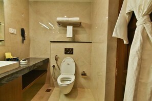 A modern bathroom with a marble floor, a white toilet, a towel rack, and a sink with a mirror. - Accord Chrome Airport Hotel (Chennai)