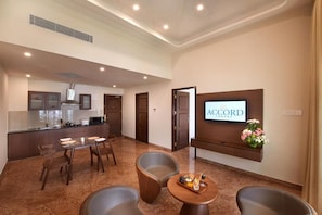 A hotel lobby with a reception desk, seating area, and a kitchen in the background. - Accord Chrome Airport Hotel (Chennai)