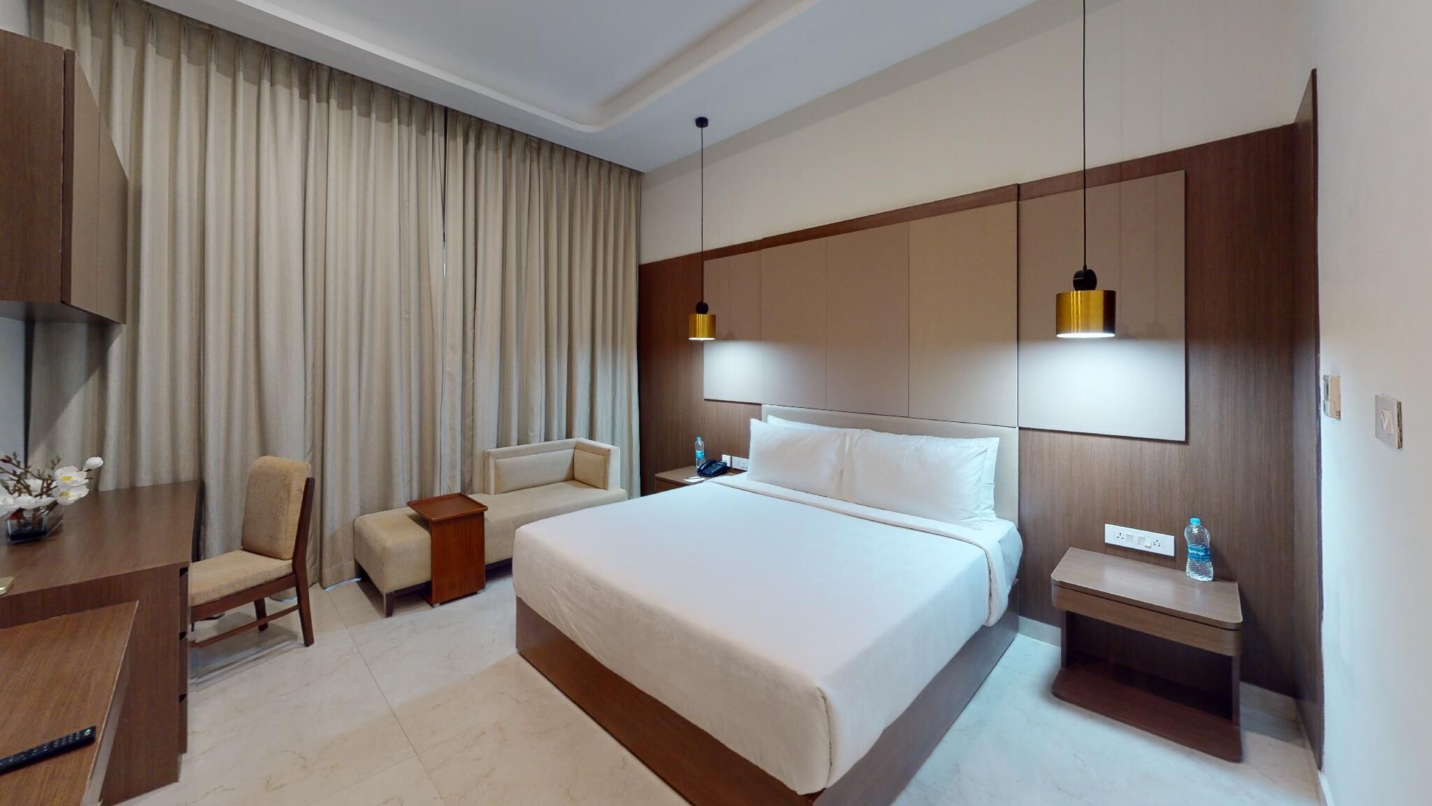 Une chambre d’hôtel avec un grand lit, un bureau, une chaise, une table de chevet et un téléviseur.