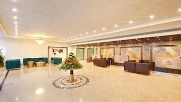 A hotel lobby with a reception desk, seating area, and a decorative centerpiece.