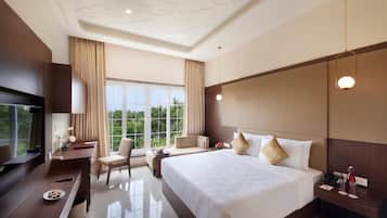 A modern hotel room with a large bed, a desk, a TV, and a view of the outdoors.