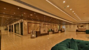 A spacious lobby with marble flooring, a green upholstered sofa, and reception desks with artwork. - Accord Chrome Airport Hotel (Chennai)