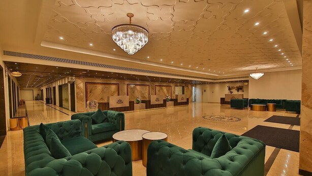 A spacious lobby with green upholstered sofas, a chandelier, and a marble floor. - Accord Chrome Airport Hotel (Chennai)