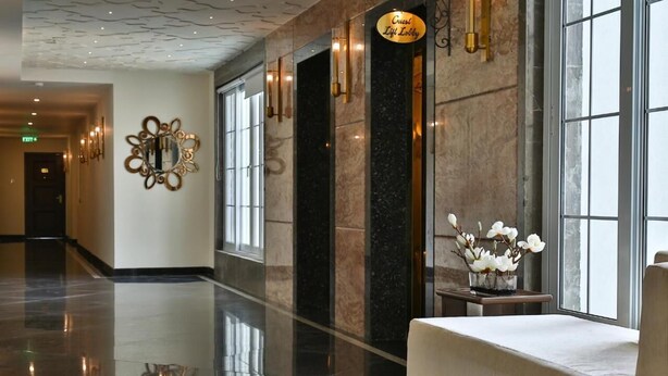A polished lobby with a reflective floor, a bench, and a wall-mounted sign indicating a guest lift lobby. - Accord Chrome Airport Hotel (Chennai)