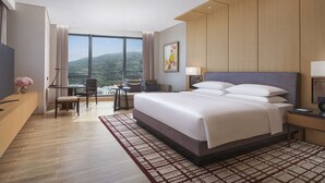 Habitació d'hotel moderna amb un llit gran, una taula de treball amb una cadira, una televisió i vistes a les muntanyes.