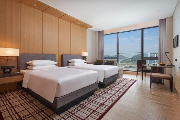 A hotel room with two beds, a desk, and a view of the city. - Hyatt Regency Hengqin (Zhuhai)