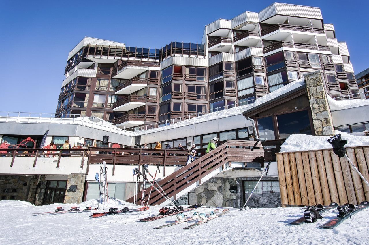 A multi-story building with balconies, ski equipment, and a wooden staircase.
