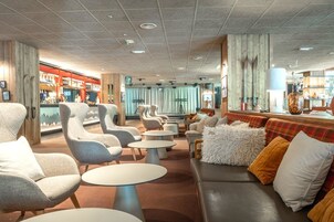 A modern lounge area with seating, tables, and a bar.