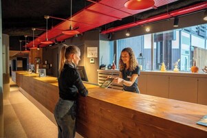 A reception area with a wooden counter, red pendant lighting, and a view of the outside.