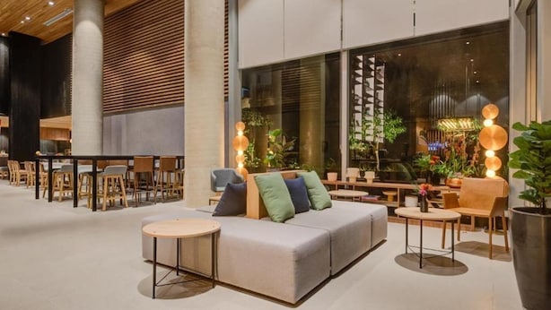 A modern indoor space with a sofa, round tables, and chairs arranged for dining or lounging. - Radisson Hotel Pinheiros, Sao Paulo (São Paulo)