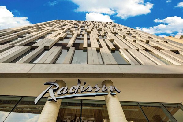 A high-rise building with a modern architectural design, featuring a prominent entrance with a sign. - Radisson Hotel Pinheiros, Sao Paulo (São Paulo)