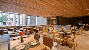A modern restaurant with wooden ceiling panels, large windows, and a variety of seating arrangements including tables and booths. - Radisson Hotel Pinheiros, Sao Paulo (São Paulo)