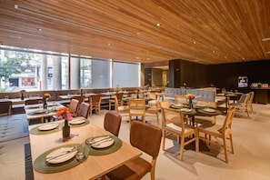 A modern restaurant with wooden ceiling panels, large windows, and a variety of seating arrangements including tables and booths. - Radisson Hotel Pinheiros, Sao Paulo (São Paulo)