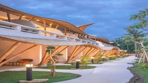 A modern building with a curved roofline and a pathway leading to it. - Pearl Sunset Resort (Gili Trawangan)