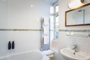 A modern bathroom with a bathtub, a sink, a glass shelf, and a shower.