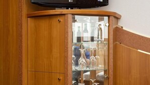 Un mobile in legno con un televisore sopra, una vetrina con bottiglie e un tappeto a righe.