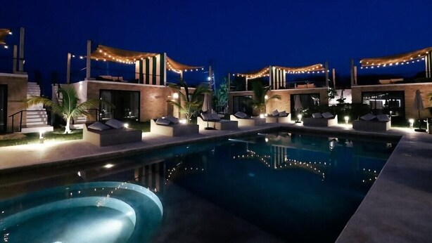 A nighttime pool area with lounge chairs and string lights. - Bora Boutique (Santa María Colotepec)
