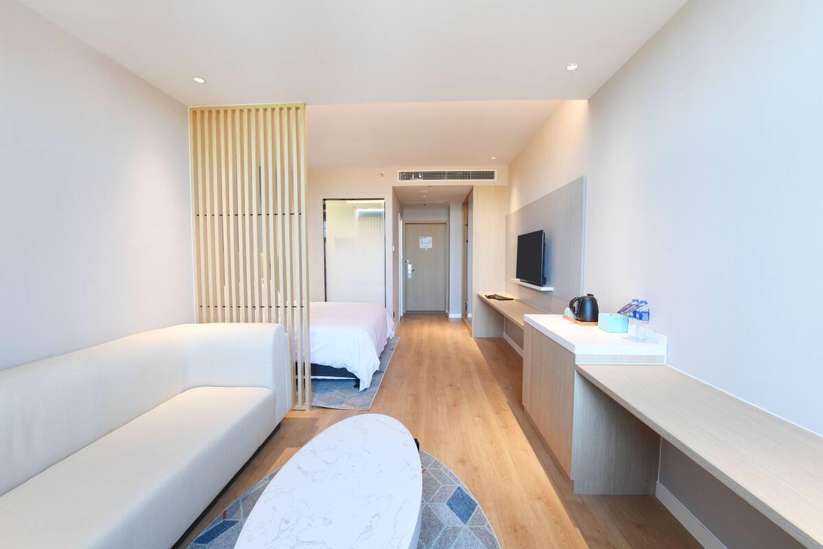 Una habitación de hotel moderna con sofá, cama, escritorio y televisión.