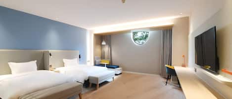 A hotel room with two beds, a desk, a TV, and a large window.