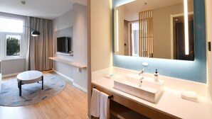 Ein modernes Badezimmer mit einem großen Spiegel, einem Waschbecken und einem runden Hocker.