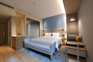 Una habitación de hotel moderna con una cama, una mesita de noche y un escritorio pequeño.