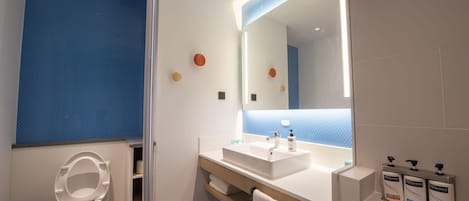 Ein modernes Badezimmer mit Toilette, Waschbecken, Spiegel und drei Handdesinfektionsmittelbehältern.