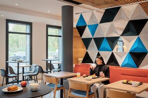 A modern cafe with tables and chairs, a large window, and a geometric wall design.