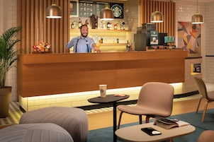 Una zona de bar con mostrador de madera, taburetes y un espacio de estar con una mesa redonda y sillas.