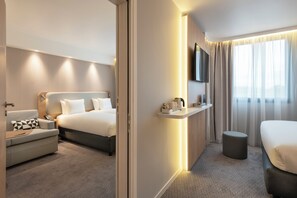 A modern hotel room with a bed, a sofa, a small table, a TV, and a window with curtains. - Holiday Inn Express Marne la Vallee Val d Europe an IHG Hotel (Bailly-Romainvilliers)