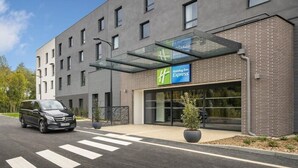 Un bâtiment de la chaîne Holiday Inn Express, doté d’un design moderne, avec un auvent d’entrée en verre et une façade en briques.