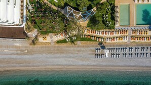 An aerial view of a resort with a pool, sun loungers, and a beach area. - Isla Brown Corinthia Resort & Spa, Curio Collection by Hilton (Loutraki-Agioi Theodoroi)