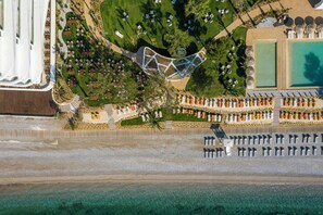 An aerial view of a resort with a pool, sun loungers, and a beach area. - Isla Brown Corinthia Resort & Spa, Curio Collection by Hilton (Loutraki-Agioi Theodoroi)