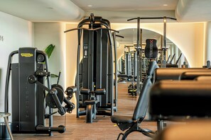 Une salle de sport équipée de divers appareils d’exercice, de bancs et dotée d’un plancher en bois.