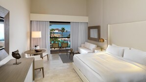 A hotel room with a bed, a desk, a chair, a lamp, and a view of a pool and beach. - W Xiamen (Xiamen)