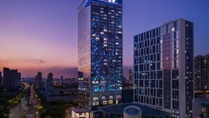 A modern high-rise building with a prominent 'W' logo at the top, surrounded by other high-rise buildings in a cityscape. - W Xiamen (Xiamen)