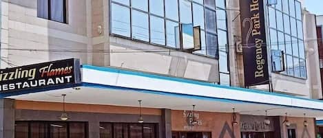 A building with a Regency Park Hotel sign, a restaurant named 'Zizzling Flames', and a motorcycle parked outside.